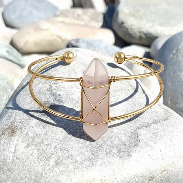 Gold bracelet with a pink crystal on a stone surface