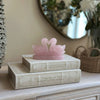 Pink swan figurine on top of a book titled 'The Tragedy of Hamlet Prince of Denmark' on a decorative surface.