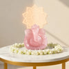 Rose Quartz Ganesha idol lit from behind on a white table with flowers