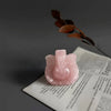 Pink ceramic object on an open book with a dark background