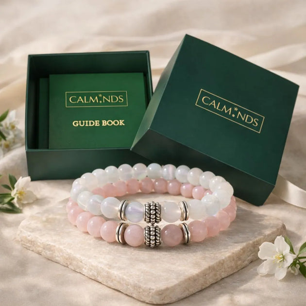 Set of pink beaded bracelets with a 'Calm Nds' guide book in a green box on a light background.