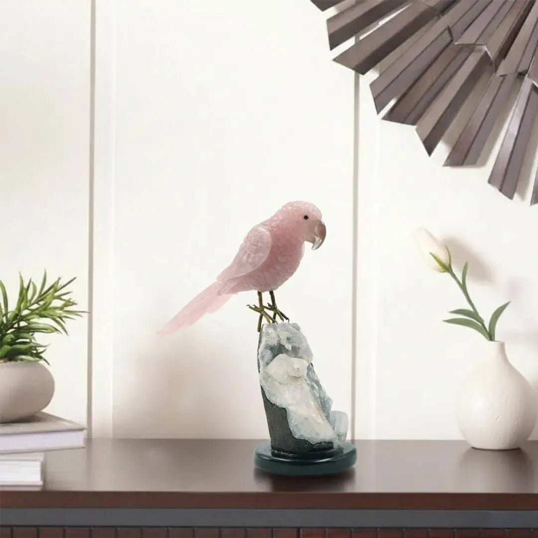 Decorative pink parrot sculpture on a stand with plants and a lamp in the background