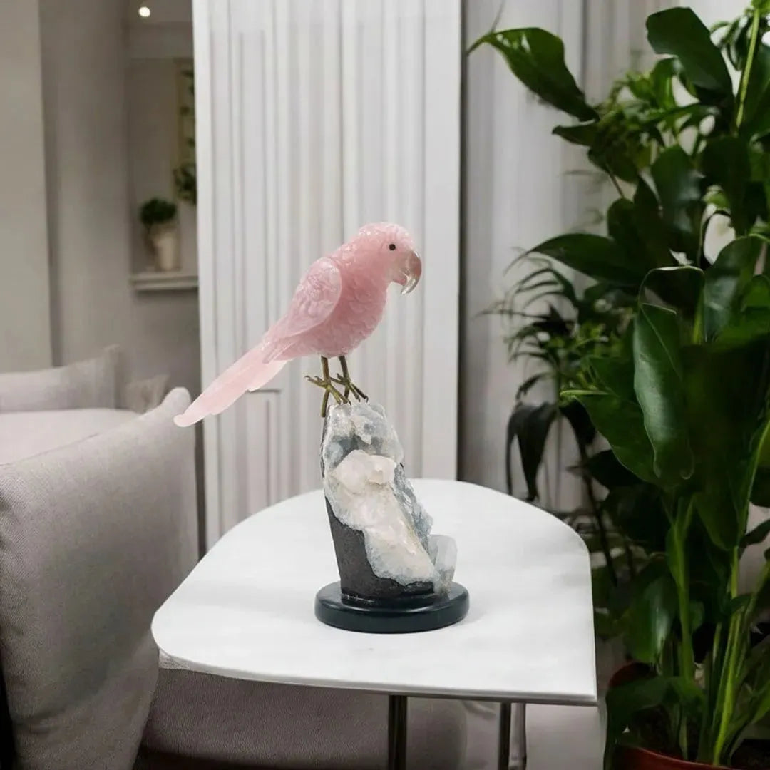 Pink parrot figurine on a white table with plants and a sofa in the background