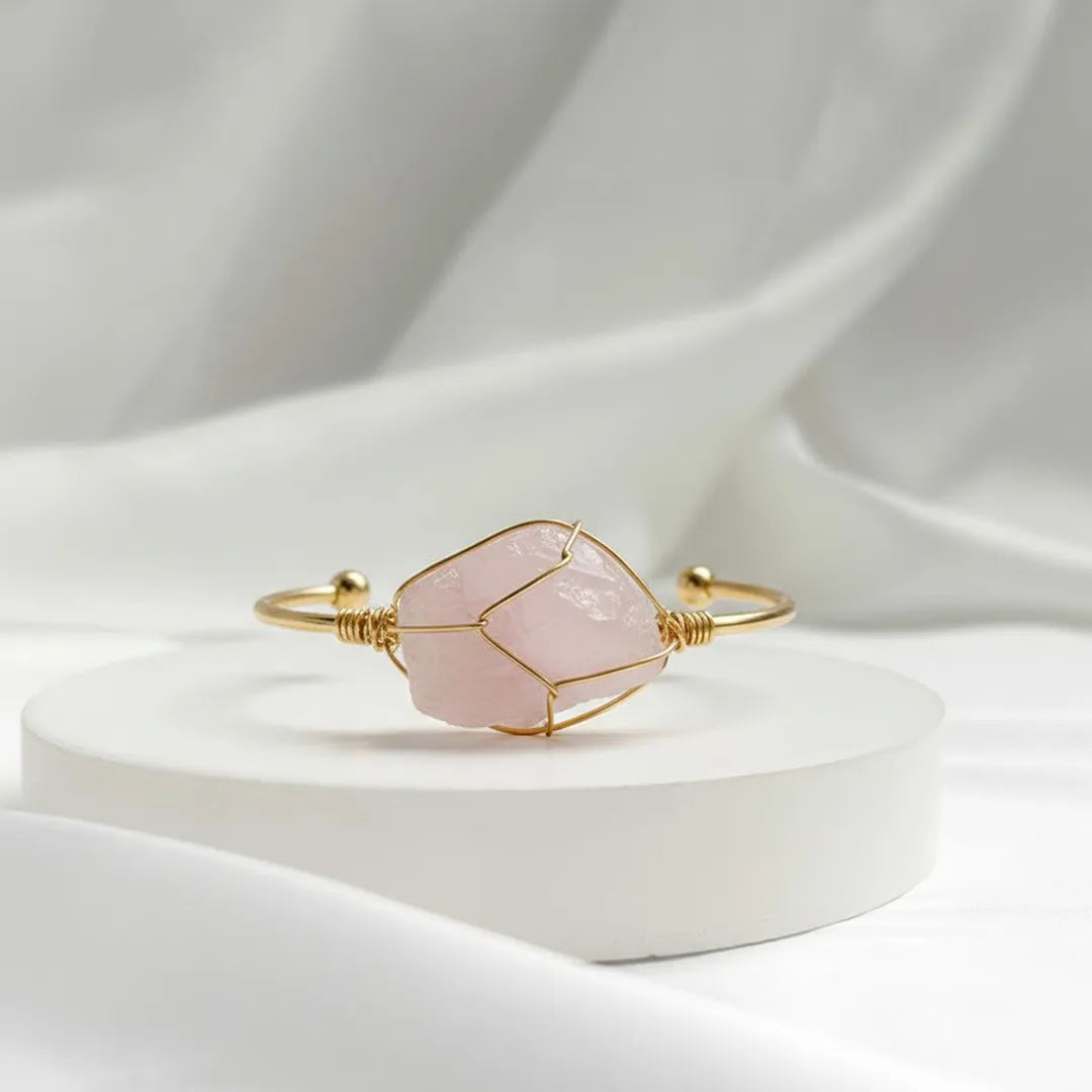 Gold bracelet with a pink stone on a white background
