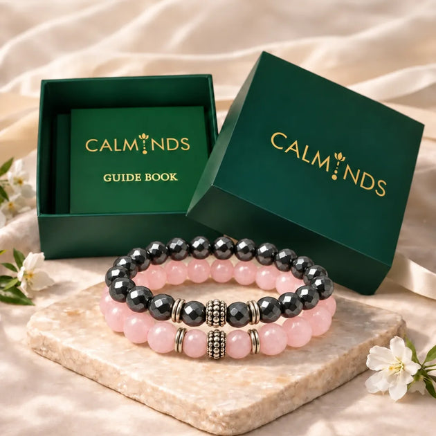 Rose quartz and silver hematite bracelets in front of a Calminds gift box and guide book