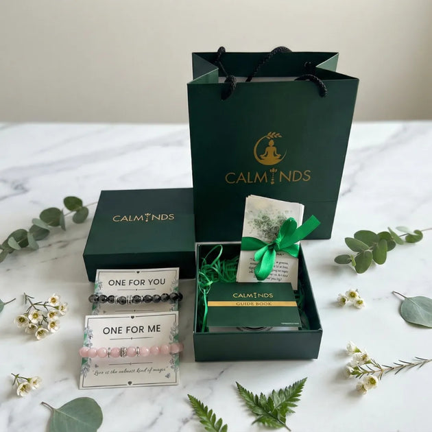 Gift set with 'Calminds' branding on a marble surface with decorative leaves and flowers.