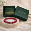 Red beaded bracelet on a round stone surface with 'CALMINDS' branded box in the background.