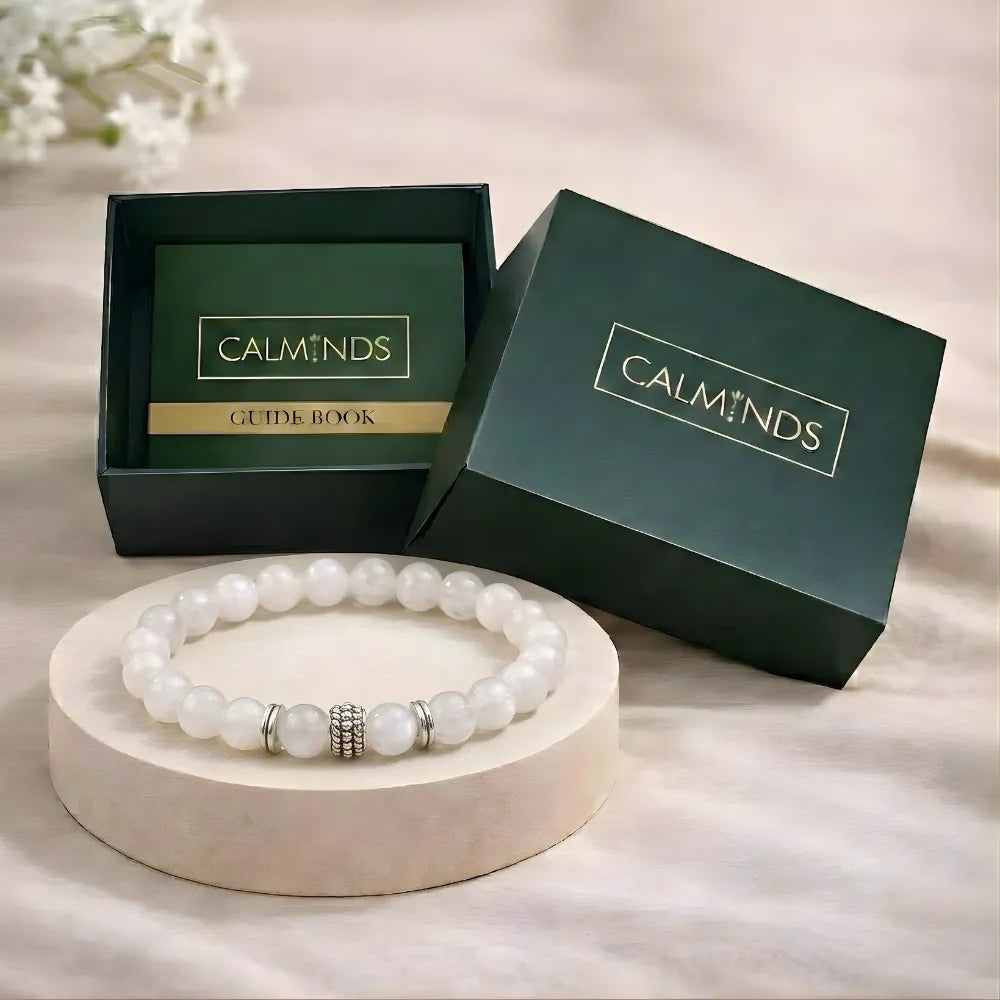 White beaded bracelet on a wooden stand with 'Calminds' branded box in the background.