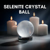 Selenite crystal ball with candles on a dark background