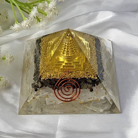 Crystal pyramid with gold and red elements on a white fabric background