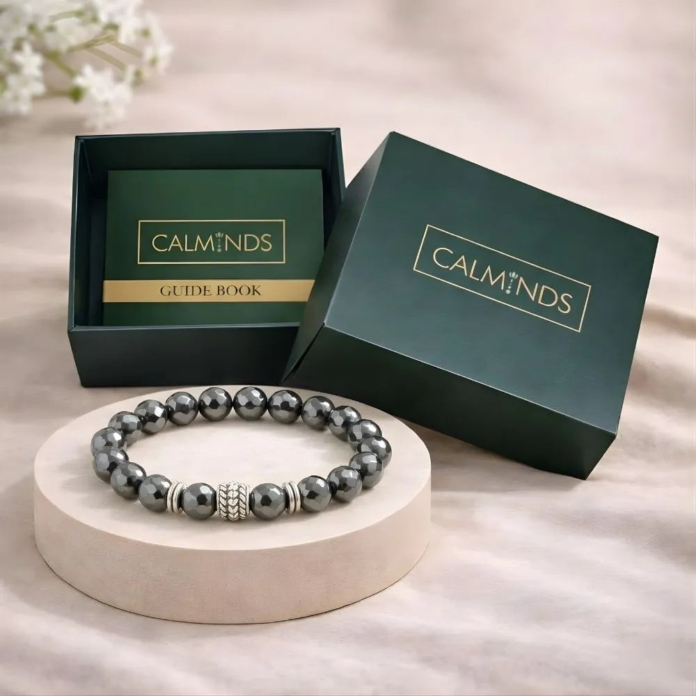 Gray beaded bracelet on a white stand with 'CALMINDS' branded box in the background