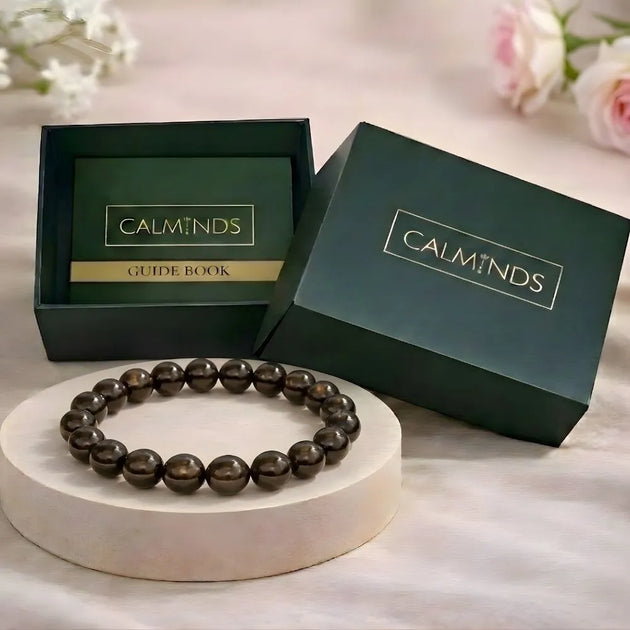 Beaded bracelet on a white stand with 'Calminds' branded box and guide book in the background.