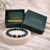 Black and blue beaded bracelet on a white stand with 'CALMINDS' branded box in the background.