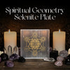 A clear acrylic or glass plate featuring a gold-colored Metatron's Key geometric symbol, displayed on a wooden surface between two lit white candles with crystals and stones around it. White text at the top reads 'Spiritual Geometry Selenite Plate'.
