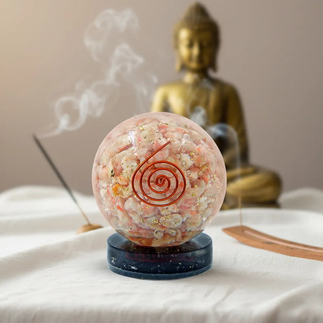 Crystal ball with a spiral symbol in front of a Buddha statue on a white surface.