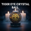 Tiger eye crystal ball with 'Tree of Life' design on a dark background with candles.