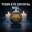 Tiger eye crystal ball with 'Tree of Life' design on a dark background with candles.