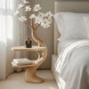 Wooden side table with floral design next to a bed in a bedroom