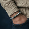 Person wearing a beaded bracelet on a dark background