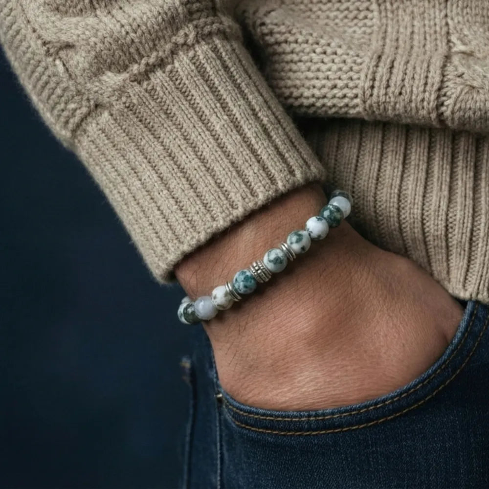 Person wearing a beaded bracelet on a dark background