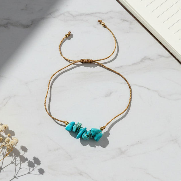thread bracelet with turquoise stones on a marble surface