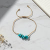 thread bracelet with turquoise stones on a marble surface