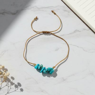 thread bracelet with turquoise stones on a marble surface
