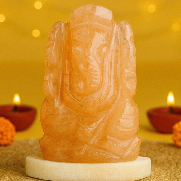 Carved yellow aventurine ganesha idol with a warm glow on a yellow background