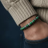 Green beaded bracelet on a wrist with a dark background